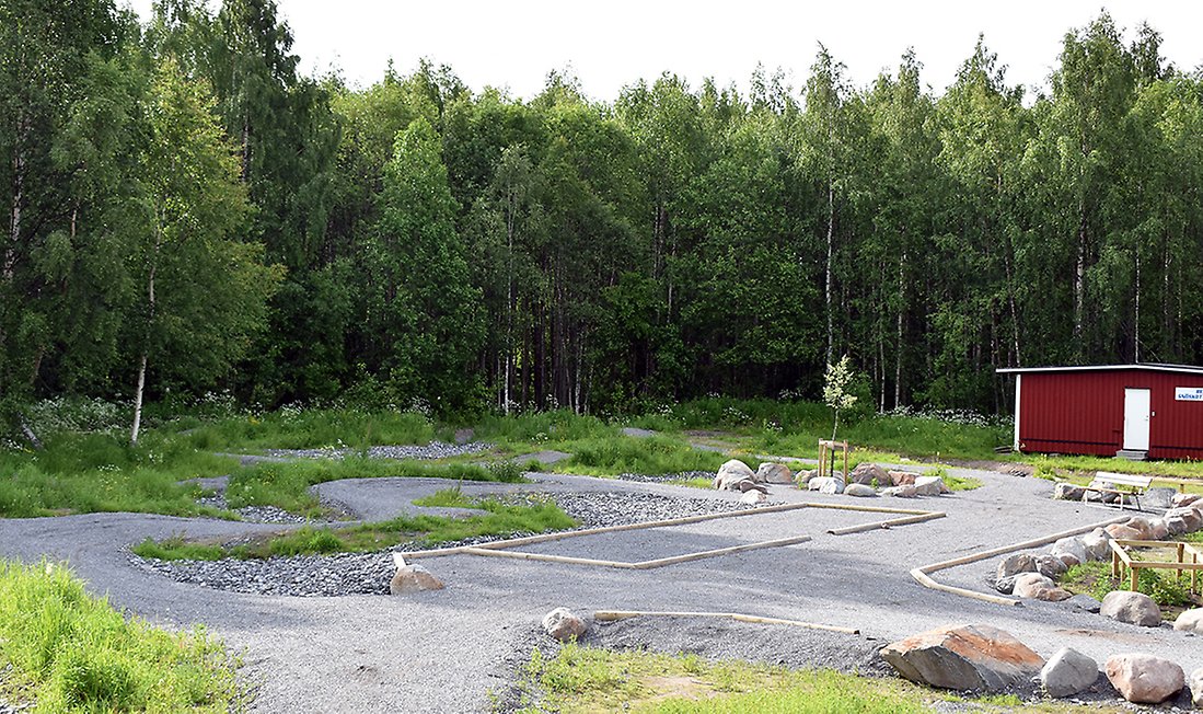 Boulbanan ligger intill skogen och cykelbanan på en grusplan. Den är kantad med natursten